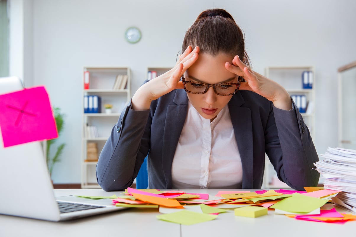 Stressed Employee Looking at Sticky Notes on Her Work Desk 